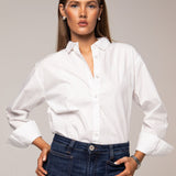 Woman wearing a white shirt and blue jeans against a neutral background
