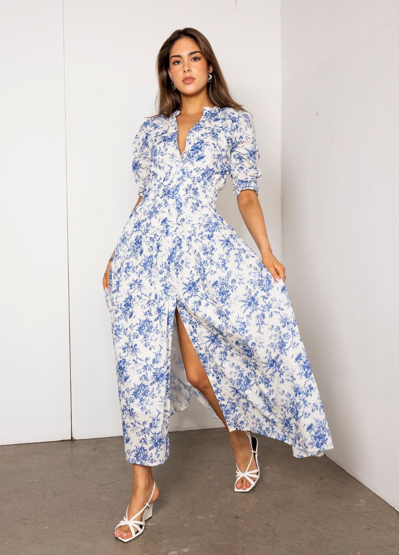 Woman wearing a blue floral dress against a white wall