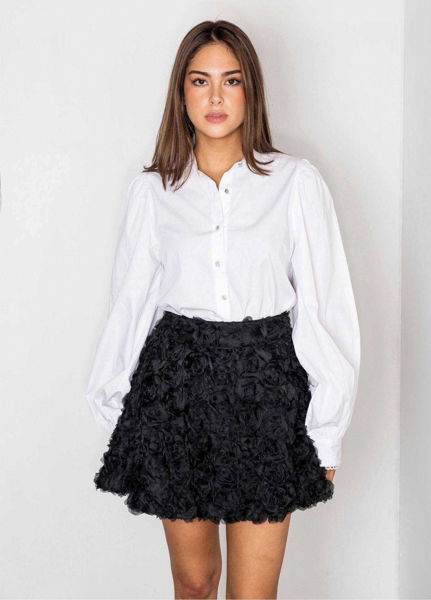 Anaya Blouse Sugar White Poplin in a front view, showing the classic collar, the button front and the full balloon sleeves finished with a fine lace edge at the cuffs. Styled with a black rosette mini skirt.
