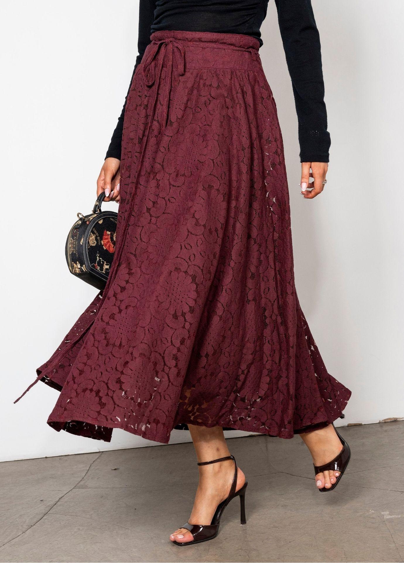 Astrid Skirt Vintage Wine in motion, a close view of the tie belt and the deep red floral lace. The model carries a small black embroidered handbag.