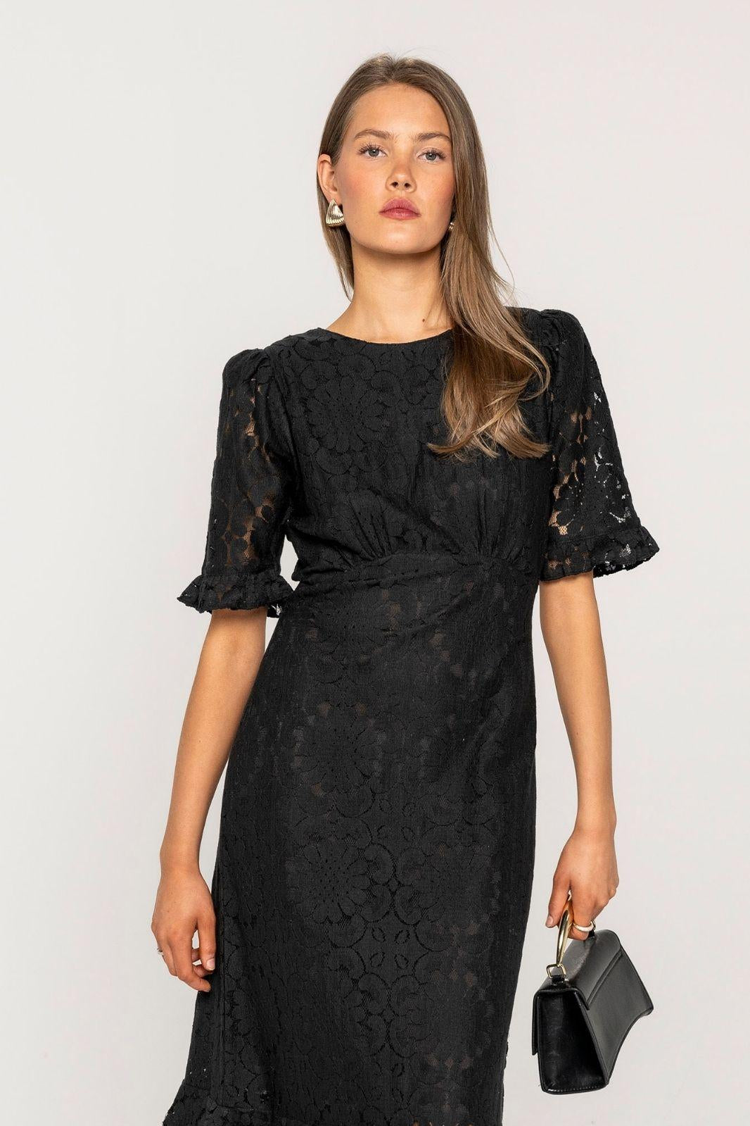 Odette Dress Noir Net in a close view, showing the gathered seam under the bust, the ruffled puff sleeves and the floral pattern of the black lace.