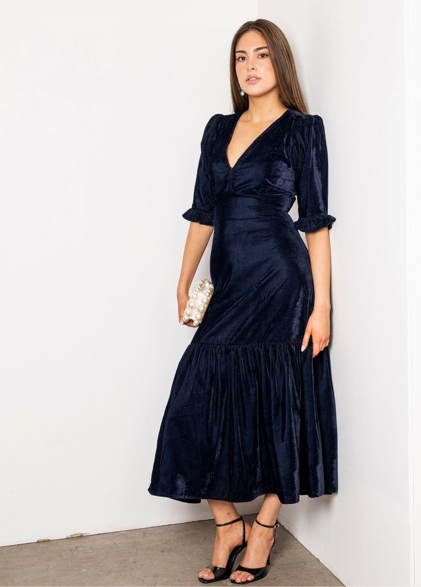 Ophelia Dress Velvet Blue Sapphire in a full length side view, showing how the fitted velvet dress opens into the flounced hem at mid calf.