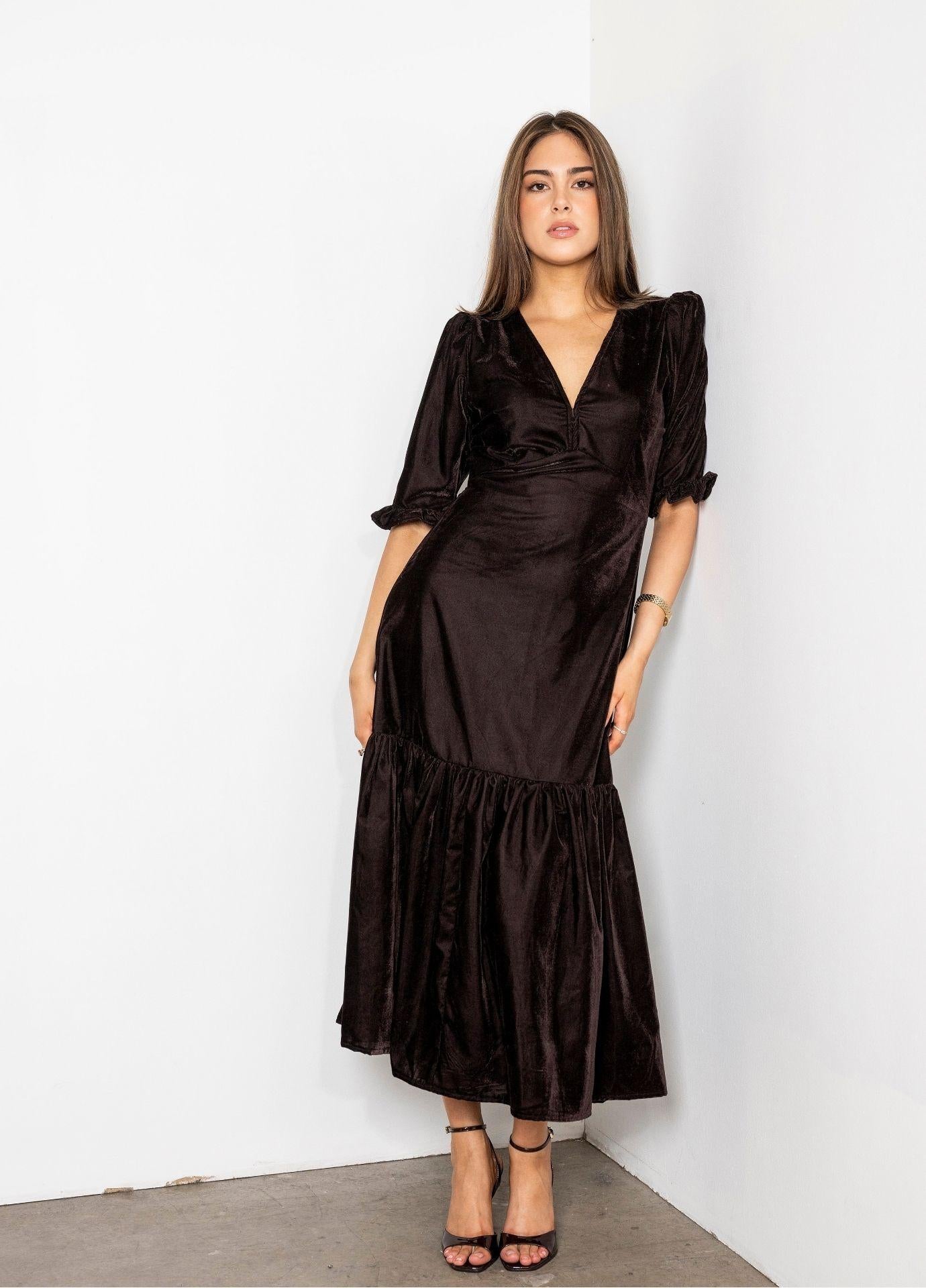 Ophelia Dress Velvet Toffee in a full length front view, showing the fitted bodice and hips opening into the flounced hem, with black strappy heels.