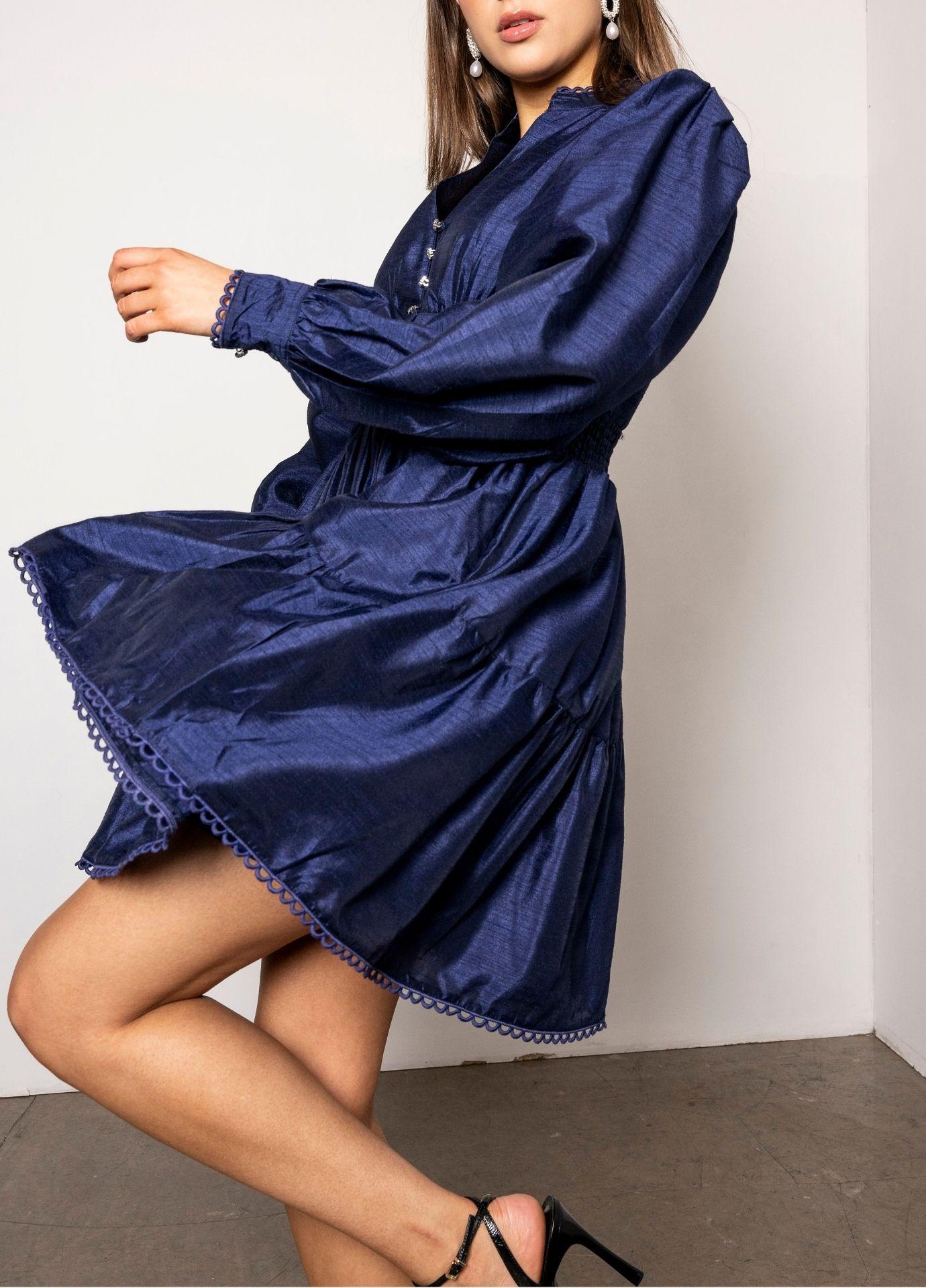 Primrose Dress Evening Blue in motion from the side, the balloon sleeves and the tiered skirt swinging out against a white wall.